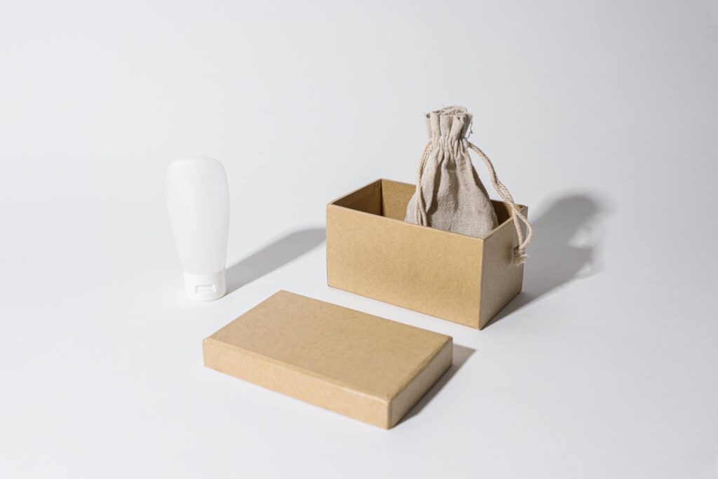 Stylish minimalist mockup featuring a cardboard box, linen pouch, and cream tube on a white background.